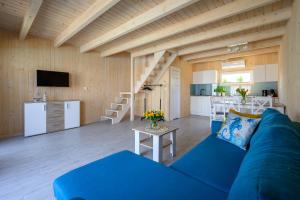 a living room with a blue couch and a kitchen at Resort Za Lasem in Jarosławiec