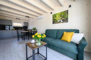 a living room with a green couch and a table at Resort Za Lasem in Jarosławiec