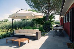 un sofá blanco y una sombrilla en el patio en Free Parking Loft a 5 minuti dal mare di Fano en Rosciano