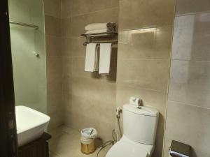 a bathroom with a toilet and a sink and towels at Amman Orchid Hotel in Amman