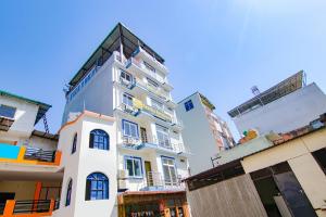 a tall white building with a black roof at Hotel Kaanha Residency Inn By Shree Krishna Hospitality in Rishīkesh