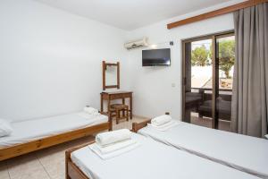 a room with three beds and a television at Nikos BnB in Faliraki