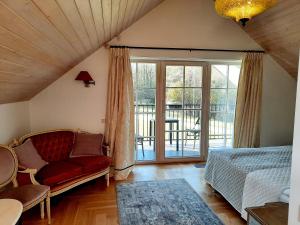 a bedroom with a couch and a sliding glass door at Lake & Library Hotel in Ignalina