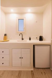 a white kitchen with a sink and a mirror at Apartments enosis, Poseidon in Agia Anna Naxos