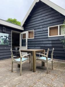 una mesa de picnic y dos sillas frente a una casa en Meer en Zee, en Scharendijke