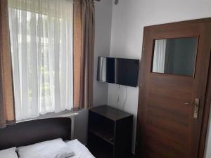 a bedroom with a bed and a door and a television at Irys 1 in Tychy