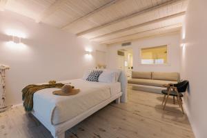 a white bedroom with a bed and a couch at Apartments enosis, Poseidon in Agia Anna Naxos
