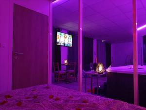 Cette chambre violette comprend un lit et une télévision. dans l'établissement CocoonSPA LoveRoom Jacuzzi, à Toulouse