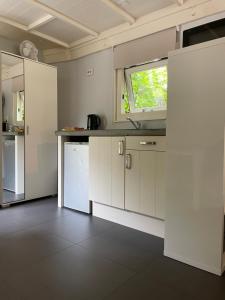 una cocina con armarios blancos y una ventana en Meer en Zee en Scharendijke