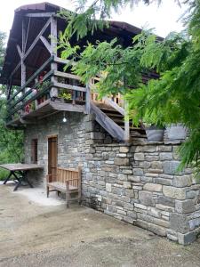 - un bâtiment en pierre avec un banc et un balcon dans l'établissement Origjina Farm, à Përmet