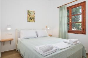 a white bedroom with a bed with towels on it at Lemon Tree Apartments Samos in Votsalákia