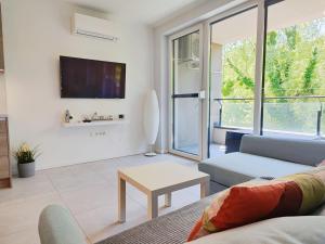 a living room with a couch and a tv at Lakeside Family & Studio Apartments in Keszthely