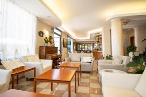 a living room with white furniture and a piano at Hotel Crystal in Caorle