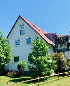 ein weißes Haus mit rotem Dach in der Unterkunft SEEMOMENTE nahe Messe, Spieleland, Friedrichshafen in Meckenbeuren