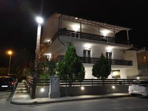 帕拉利亚卡泰里尼斯Villa Olympia的一座白色的建筑,在晚上前方有树木