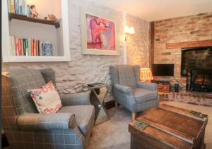 a living room with two chairs and a fireplace at Tubs Cottage in Kingsteignton