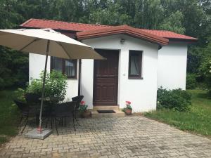 ein kleines weißes Haus mit einem Tisch und einem Sonnenschirm in der Unterkunft Maly bialy domek pod brzozami in Nałęczów