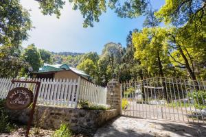 Ein weißer Zaun mit einem Schild davor. in der Unterkunft Dalhousie Heritage Cottage in Nainital