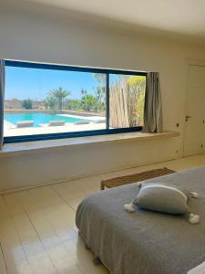 - une chambre dotée d'une grande fenêtre offrant une vue sur la piscine dans l'établissement Villa Nausikaa Essaouira, Villa d'architecte luxe avec piscine, à Essaouira