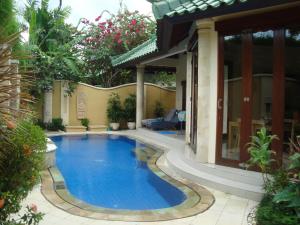 a swimming pool in front of a house at Bali Emerald Villas in Sanur