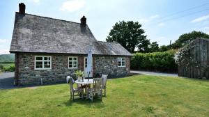 a table and chairs in front of a stone house at Country Cottage with Far Reaching Views in Presteigne