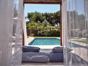 uma vista para uma piscina a partir de um alpendre com cortinas em La Maison Du Maire Luxury Villa em Sarakinádhon