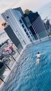 BASE Central PATTAYA Long Balcony with Infinity Pool & Free Netflix! في باتايا سنترال: شخص في تجمع مياه امام المباني