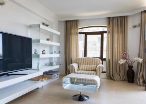 ein Wohnzimmer mit einem TV und einem Stuhl in der Unterkunft Oasis club apartments in Lozenets