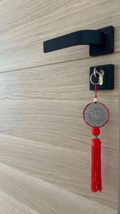 una nappa rossa appesa a una porta con una chiave di VILLA HOLISTIKA : BED AND BREAKFAST / POOL / AIR CONDITIONING/ MONT FARON TOULON a Tolone
