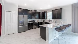 ダベンポートにある9028SH-The Retreat at ChampionsGate homeの黒いキャビネット付きのキッチン、バースツール付きの大きな島 +29枚の写真