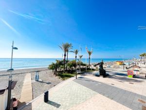 a sidewalk next to a beach with palm trees and the ocean at Apartment on the 1st line of the Sabinillas beach with sea views in San Luis de Sabinillas