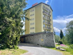 a tall building with a stone wall in front of a building at Tatry Ela Big in Štrbské Pleso