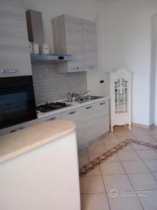 uma cozinha com armários brancos e piso em azulejo em House 123 em Sorso