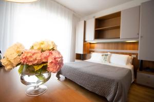 1 dormitorio con 1 cama y un jarrón de flores en Hotel Crystal, en Caorle
