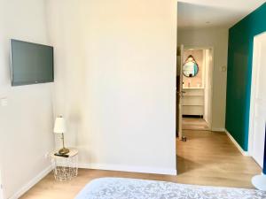 a bedroom with a white wall and a bed and a television at Logis des vignes in Saint-Émilion