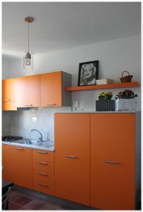 una cucina con armadi arancioni e lavandino di Appartamenti Mirabella a Favignana