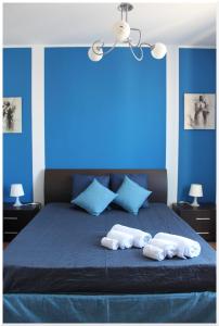 una camera da letto con pareti blu e un letto con due asciugamani laminati di Appartamenti Mirabella a Favignana