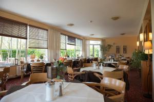 a restaurant with tables and chairs and windows at Montana Hotel Senden in Senden