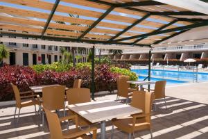 a patio with tables and chairs and a swimming pool at Apartamentos Charco del Conde in Valle Gran Rey