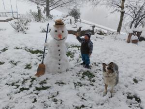 un hombre y un perro parados junto a un muñeco de nieve en Stockachhof, en Fügenberg