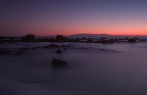a sunset over the ocean with rocks in the foreground at Apartamentos Charco del Conde in Valle Gran Rey
