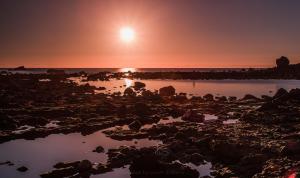 a sunset on the beach with rocks and water at Apartamentos Charco del Conde in Valle Gran Rey