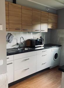 a kitchen with white cabinets and a sink and a microwave at Ferienhaus "Zauberwald" mit Pelletofen & Sauna in Meschede