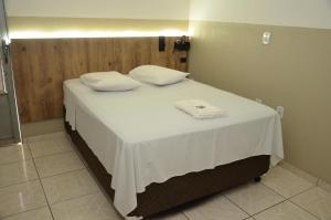 a bed with two white towels on top of it at HOTEL VITORIA REGIA in Engenheiro Beltrão