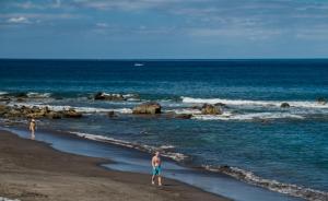 two people standing on a beach near the ocean at Apartamentos Charco del Conde in Valle Gran Rey
