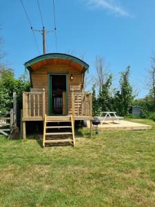 a small cabin with a porch and a deck at Woodie the shepherds hut - sleeps 4 in Chichester