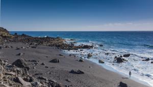 a person standing on a beach near the ocean at Apartamentos Charco del Conde in Valle Gran Rey
