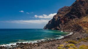 a beach with a mountain and the ocean at Apartamentos Charco del Conde in Valle Gran Rey