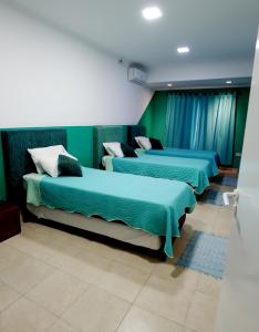3 Betten in einem Zimmer mit grünen Wänden in der Unterkunft ALQUIMIA in Paso de la Patria