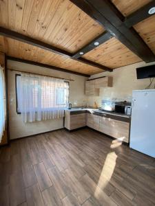 a large kitchen with wooden ceilings and a white refrigerator at Воллен in Zhvanets